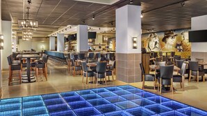 A modern restaurant with a bar area, multiple dining tables, and chairs. - Embassy Suites by Hilton Round Rock (Round Rock)