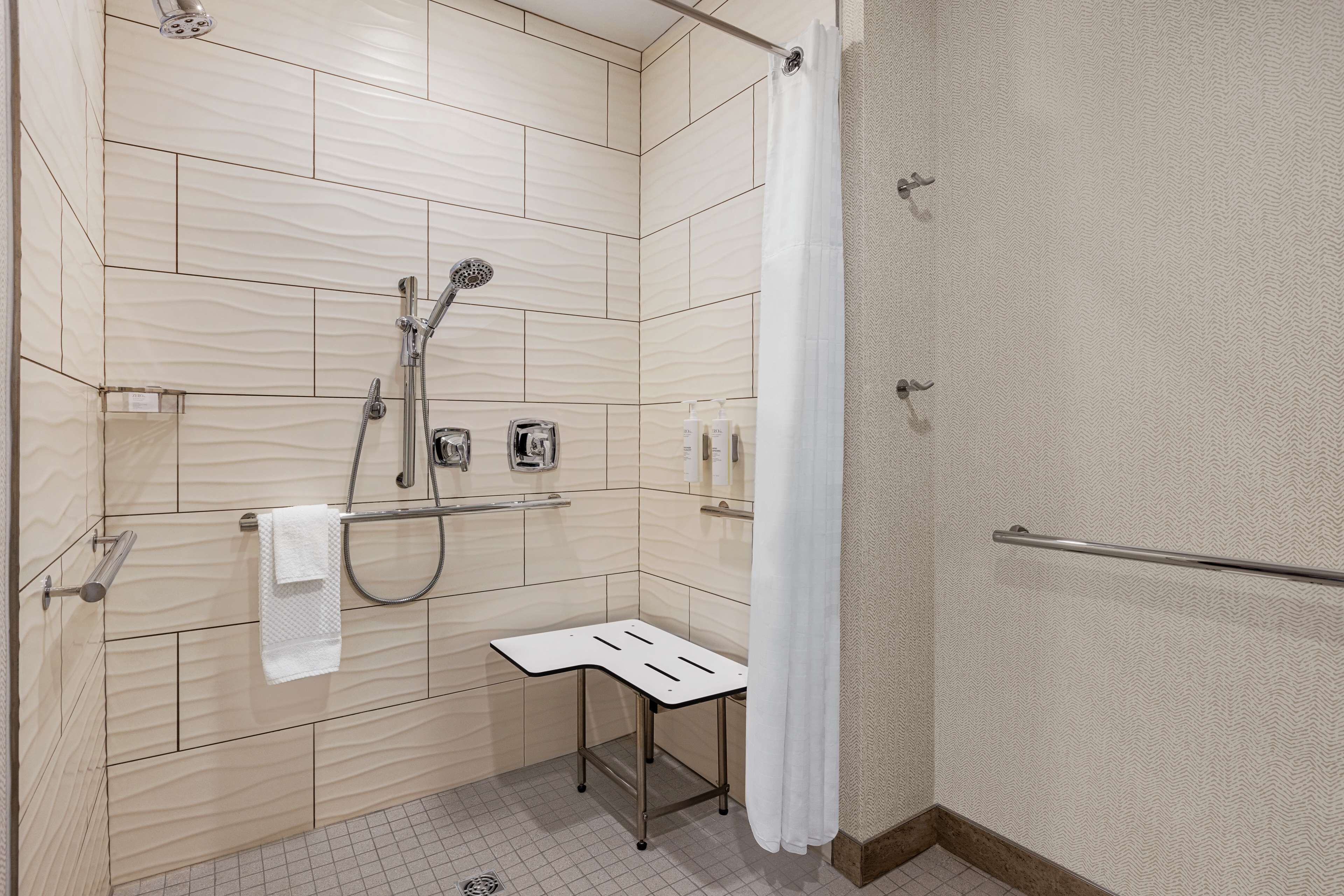 Un baño moderno con ducha, perchero y un taburete pequeño.
