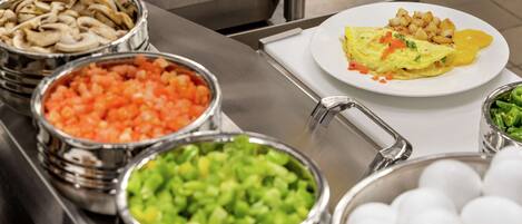 A buffet with various food items including mushrooms, tomatoes, green vegetables, and eggs.