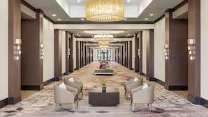 A hotel lobby with a long corridor, seating areas, and chandeliers. - Embassy Suites by Hilton Round Rock (Round Rock)