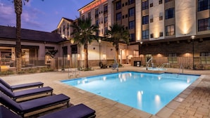 Un hôtel Hilton Garden Inn doté d’une piscine, de chaises longues et de palmiers.