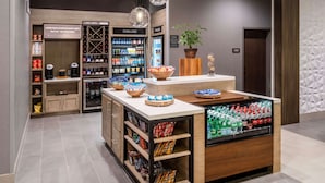 Un café moderne doté d’un bar à café, d’un espace proposant des boissons fraîches et glacées, et d’un présentoir de snacks.