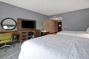 A hotel room with a large bed, a desk with a chair, a TV, and a mirror. - Hampton Inn And Suites Deptford (Woodbury)
