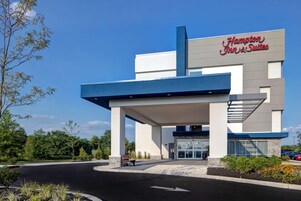 A Hampton Inn & Suites hotel with a modern design, featuring a prominent entrance and a clear sky.
