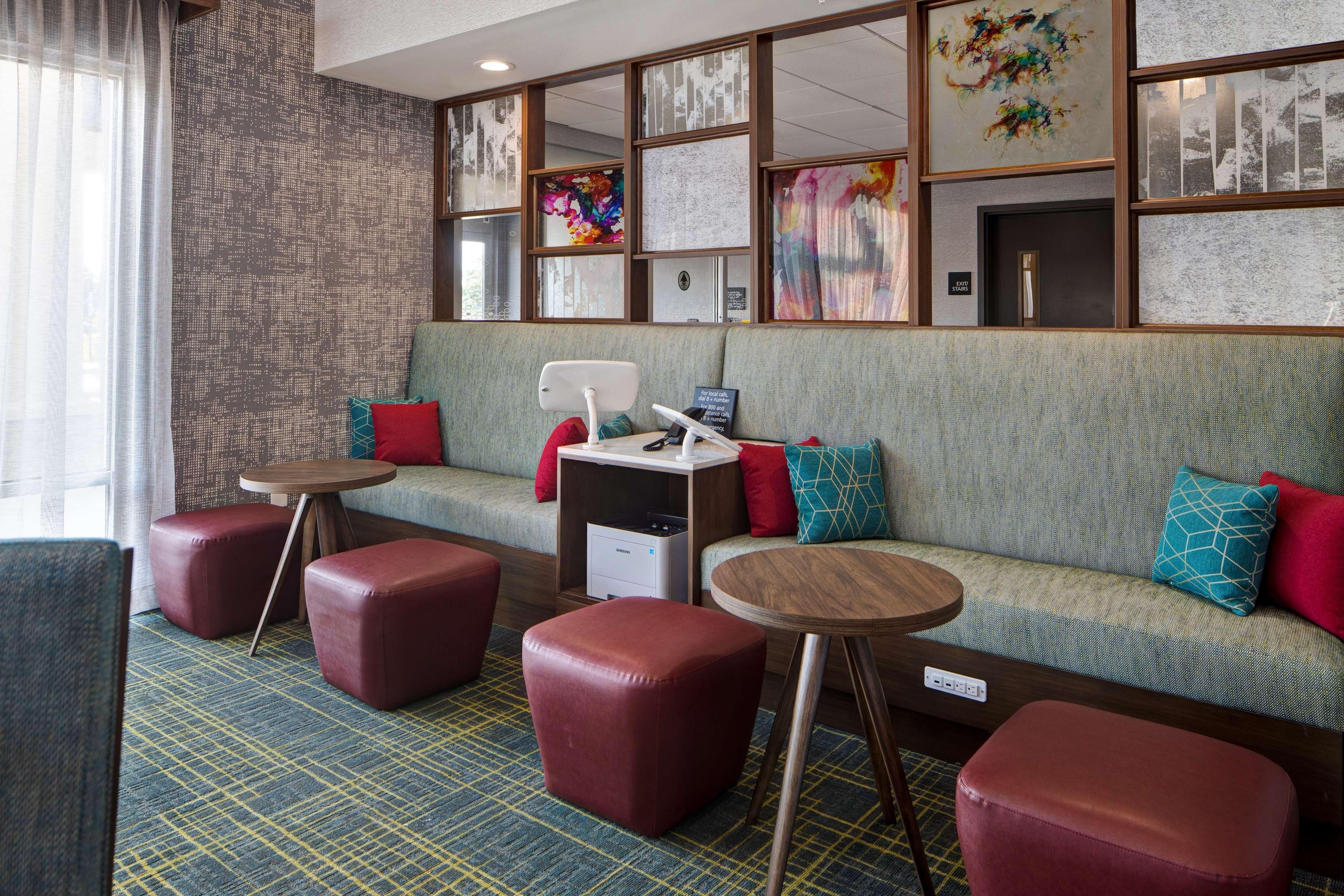 A hotel room with a sofa, two ottomans, a small table, and a desk with a computer.