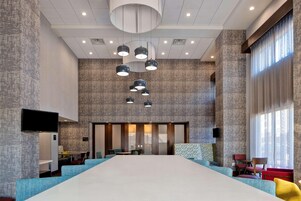 Una amplia sala de conferencias con una larga mesa, múltiples sillas y un diseño de techo moderno.
