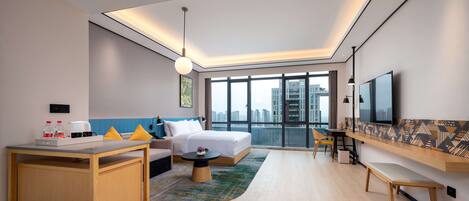 A modern hotel room with a bed, desk, and seating area.