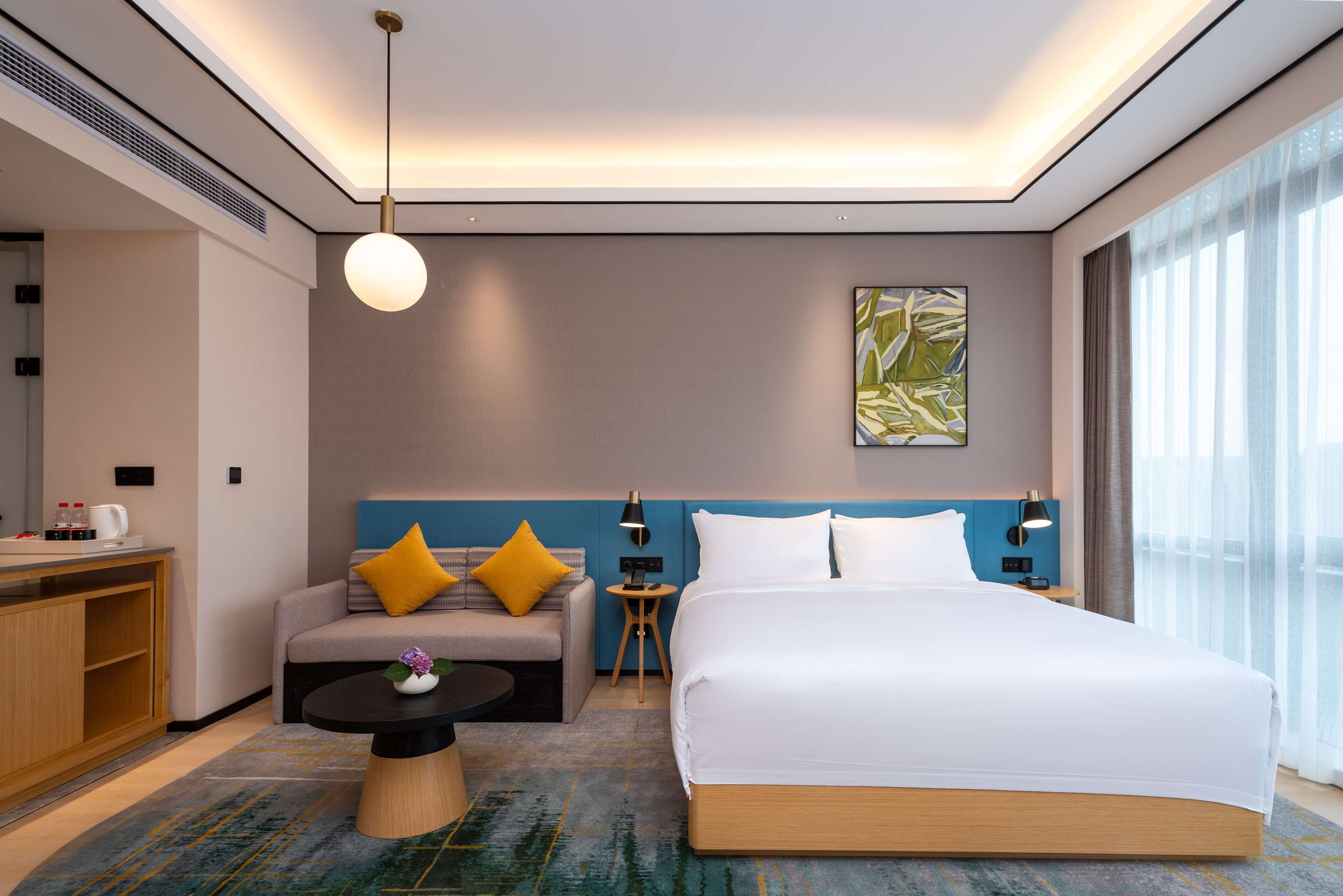 Een moderne hotelkamer met een groot bed, een bank, een tafeltje en een bureau.