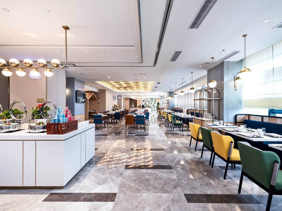 A modern restaurant with a central island, multiple dining tables, and a variety of seating options.