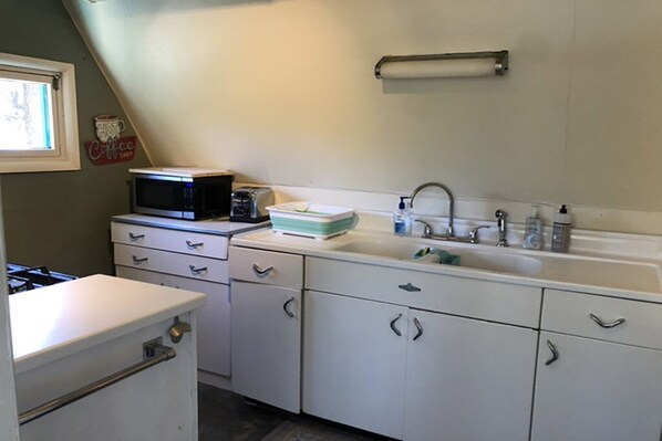 A kitchen with white cabinets, a microwave, a toaster, and a sink.