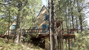 Eine Holzhütte mit einer Holzterrasse und einer kleinen Brücke, die sie mit einer unteren Ebene verbindet.