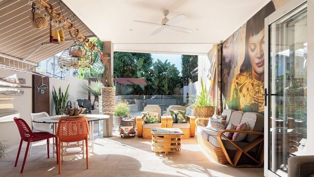 A spacious patio with a dining area, seating, and a large mural.