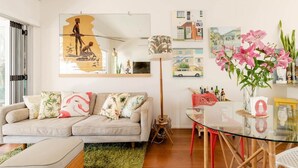 A modern living room with a sofa, a glass coffee table, and a dining area with chairs.