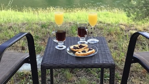 Une table avec deux boissons et une assiette de nourriture, près d’un lac.