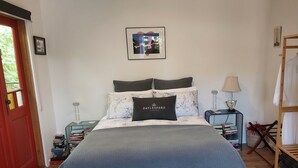 Une chambre à coucher bien rangée, avec un lit, des oreillers, une table de chevet, une lampe et une armoire.
