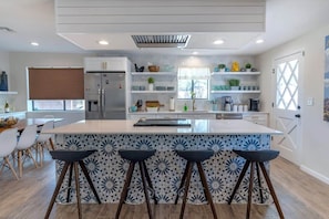 A modern kitchen with a central island, bar stools, and built-in shelves.