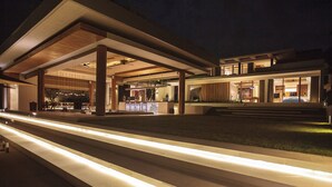 A modern building with a covered outdoor area, a well-lit entrance, and a visible staircase leading to the main entrance. - Where Tranquility Meets Luxury – Bali Villa 1071 (Bali)