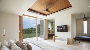 A bedroom with a large bed, a sliding glass door to a balcony, a ceiling fan, and a TV on the wall. - Where Tranquility Meets Luxury – Bali Villa 1071 (Bali)