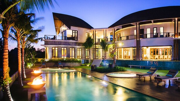 Ein modernes, zweistöckiges Haus mit Swimmingpool, Außenbereich zum Sitzen und einer gut beleuchteten Terrasse.