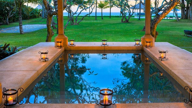 A serene pool area with a glass bottom, surrounded by stone walls and lit by candle sconces. - 5-Star Beachfront Villa, Bali Villa 1014 (Bali)