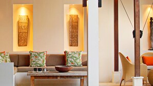 A modern living room with a sofa, a coffee table, and two wall-mounted light fixtures. - Elegant Cliffside Villa with Breathtaking Views – Bali Villa 1031 (Bali)