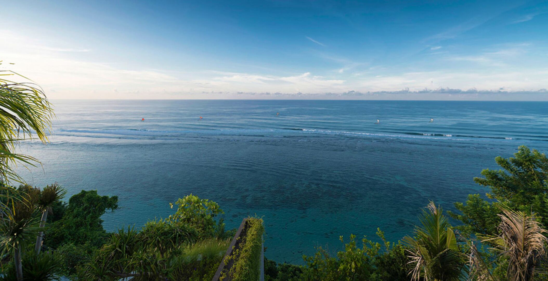 A coastal view with a clear sky, calm sea, and lush greenery.