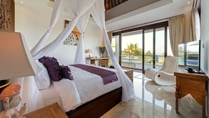 Un dormitorio con cama con dosel, televisión, una silla y un balcón con vistas.