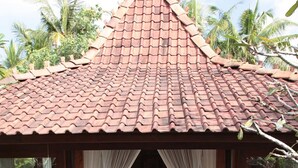 A traditional-style room with a tiled roof, a bed with white linens, and a small table.