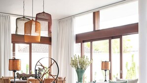 A modern living room with a white sofa, decorative pillows, a round coffee table, and a large window with curtains. - Stylish Beachside Villa with Pool & Stunning Views – Bali Villa 1068 (Bali)