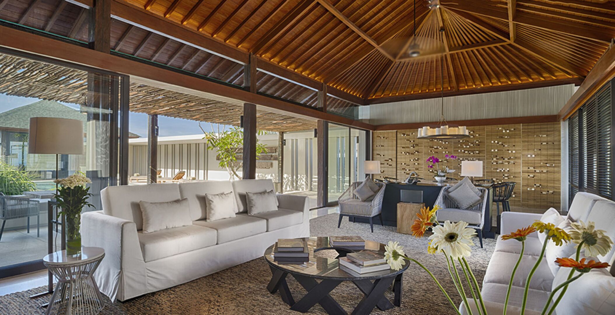 A spacious living area with a large sofa, a coffee table, and a dining area with chairs.
