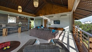 A spacious living area with a large gray sofa, a wooden coffee table, and a TV mounted on the wall. - Bali Villa 1029: Where Luxury Meets the Sky (Bali)