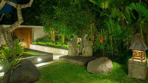 A well-lit garden with stone sculptures, a pathway, and lush greenery. - Bali Villa 1029: Where Luxury Meets the Sky (Bali)