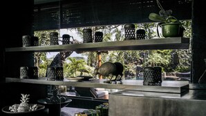 A kitchen with a view of a tropical garden, featuring a shelf with decorative jars and a small statue of a bird. - Luxury Villa Escape with Exceptional Staff – 1028 (Bali)