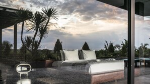 A modern bedroom with a bed, pillows, and a view of palm trees and a cloudy sky. - Luxury Villa Escape with Exceptional Staff – 1028 (Bali)