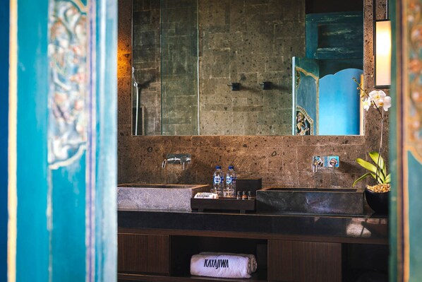 A bathroom with a stone sink, a mirror, and a towel rack.