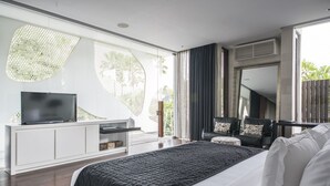 Ein modernes Schlafzimmer mit einem großen Bett, einem Fernseher auf einem weißen Schrank und Blick auf Grün.