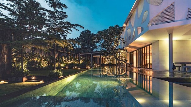 Ein modernes Haus mit Swimmingpool, umgeben von üppiger Vegetation und einem gut beleuchteten Außenbereich.