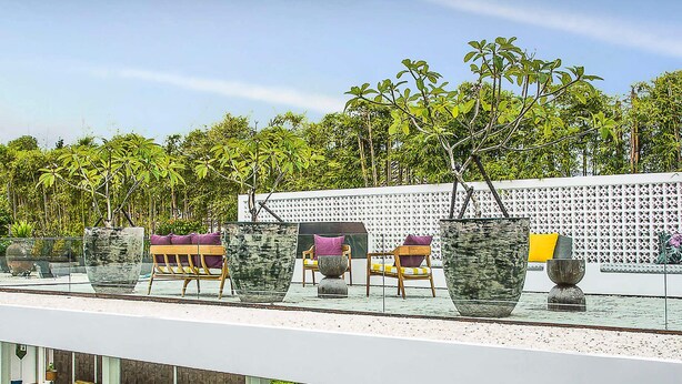 A modern outdoor seating area with a pool, featuring a white railing, multiple chairs, and large planters. - Bali Villa 1010: Ultimate Luxury Retreat with Private Pool (Bali)