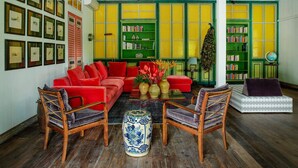 A room with a red sofa, wooden chairs, a blue and white vase, and green and yellow bookshelves. - Bali Villa 1010: Ultimate Luxury Retreat with Private Pool (Bali)