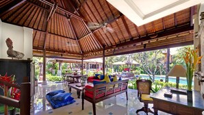 A spacious indoor area with a high ceiling, a ceiling fan, and a view of a pool outside.