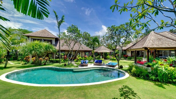 A resort with a central swimming pool, multiple bungalow-style accommodations, and lush tropical landscaping.