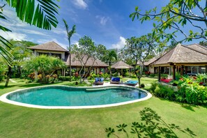 Un resort con piscina central, múltiples alojamientos tipo bungalow y exuberante jardinería tropical.