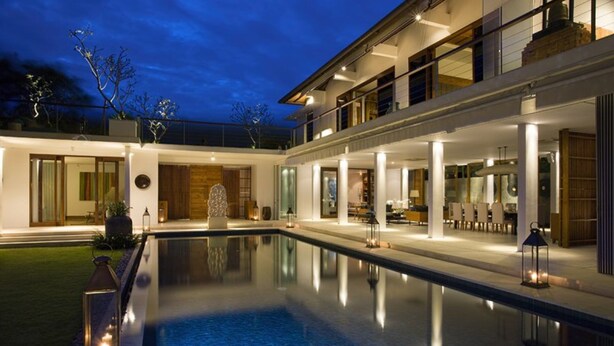 Et moderne hus med swimmingpool, store vinduer og et godt oplyst udendørsareal.
