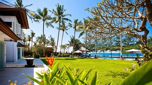 Un resort con piscina, palmeras y sillones de descanso.