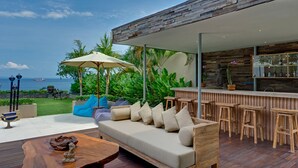 An outdoor seating area with a sofa, chairs, and a bar.