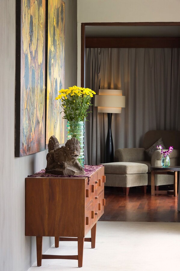 A modern living room with a wooden sideboard, a vase with yellow flowers, a lamp, and a sofa.