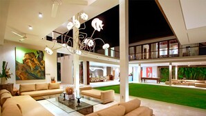 A spacious living area with a modern chandelier, a large painting, and a view of the outdoor garden. - Exclusive Luxury Villa with Pool & Entertainment – Bali Villa 1059 (Bali)