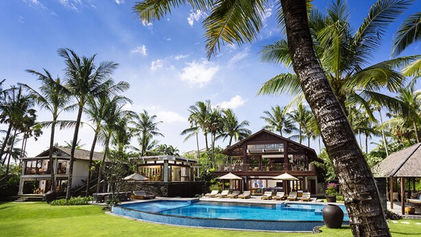 A resort with a swimming pool, multiple guest houses, and palm trees.