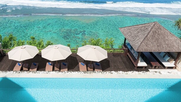 A resort with a pool, lounge chairs, and umbrellas overlooking a clear blue sea. - Cliffside Retreat with Pool & Ocean Views – Bali Villa 1065 (Bali)
