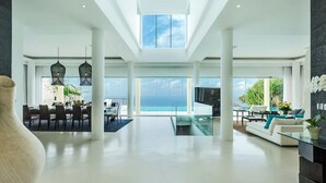 A spacious, modern interior with a high ceiling, large windows, and a view of the ocean. - Cliffside Retreat with Pool & Ocean Views – Bali Villa 1065 (Bali)